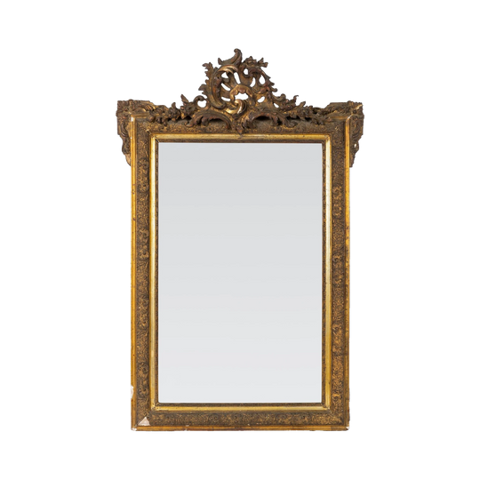 Ornately carved giltwood Louis XV-style mirror with Rococo detailing and a dramatic crest with intricate detailing throughout the frame. Found in Provence
