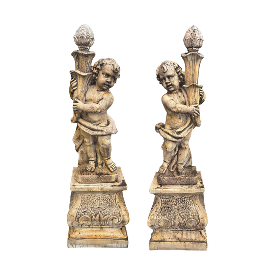 A pair of cast limestone cherub garden statues figures on stands
