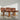 A rare set of 4 vintage Joe Rufenacht lounge chairs in Howe leather, featuring tufted backs and wooden frames, are arranged in a sunlit room with a gray floor and plain white wall.