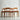 A set of four fully restored THB 'Milan' dining chairs (Rediscover), featuring minimalist mid-century modern design, is arranged in a staggered row against a plain light gray wall. Each chair has curved backrests and light brown upholstered seats.