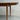 A close-up of the Fully Restored Parker 140 Square Extension Table (Rediscover) with tapered legs and an extending leaf, set against a plain light gray concrete wall and floor.