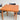 The Fully Restored Parker 140 Square Extension Table (Rediscover), featuring a light brown finish and mid-century modern design, is paired with two black chairs against a plain light grey background.
