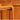 A close-up of a wooden chair leg and armrest, with a blurred Mid-Century Noblett Drinks Trolley – Removable Tray & Original Castors (Revive) featuring round handles in the background. Warm lighting highlights the wood grain and texture.