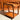 The Mid-Century Noblett Drinks Trolley – Removable Tray & Original Castors (Revive) features a minimalist design with curved edges, two shelves, and four caster wheels. Sunlight casts shadows on the trolley and nearby wooden cabinets.