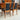 A set of 4 fully restored Noblett T-Back 'Boston' dining chairs in black vinyl is arranged together in a room with a wooden sideboard and mid-century modern decor.