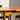 A close-up of the Vintage Parker Dining Suite 5 Piece Square - Number 140, featuring a wooden table with rounded legs and two matching chairs in black frames, all set in sunlight against a pale wall—Scandinavian-inspired Australian design.