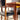 Close-up of the Vintage Parker Dining Suite 5 Piece Square - Number 140, featuring curved-leg chairs with black seat cushions. Sunlight highlights the wood grain, creating a warm and inviting mid-century vintage ambiance.
