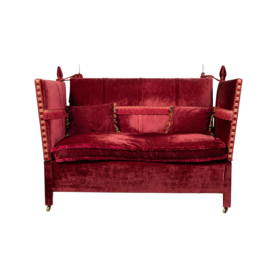 Cherry red velvet knole sofa with drop arms, braid and fringed passementerie and tie-backs