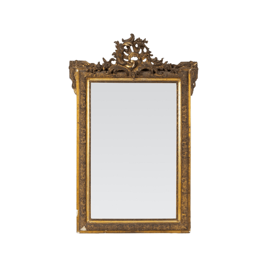 Ornately carved giltwood Louis XV-style mirror with Rococo detailing and a dramatic crest with intricate detailing throughout the frame. Found in Provence