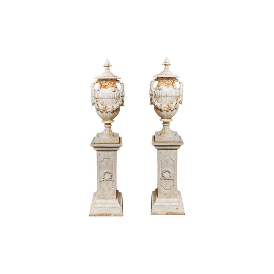 Pair of cast iron urns on pedestals