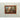 Full framed view of the vintage street scene oil painting displayed against a pale concrete wall.